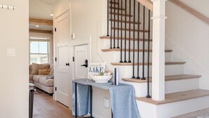A staircase with wooden steps and black balusters, a small table with a blue cloth, and a sign on the wall. - Lakeside 2-bedroom condo in awesome Laconia (Laconia)