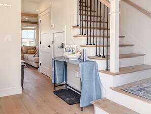A staircase with wooden steps and black balusters, a small table with a blue cloth, and a sign on the wall. - Lakeside 2-bedroom condo in awesome Laconia (Laconia)