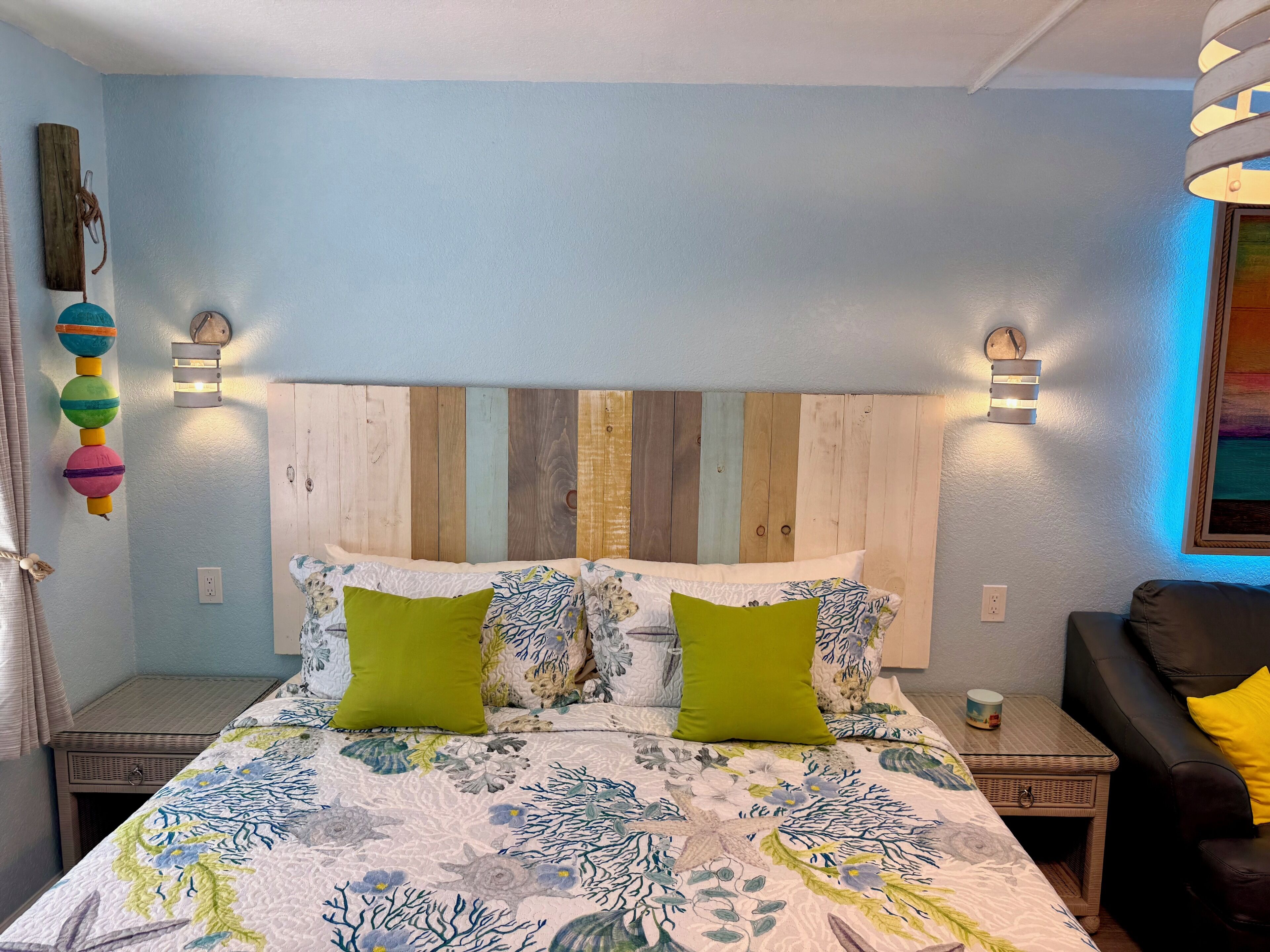 Ein Schlafzimmer mit einem Bett, zwei Nachttischen, einer Wandleuchte und einem Wandbild.