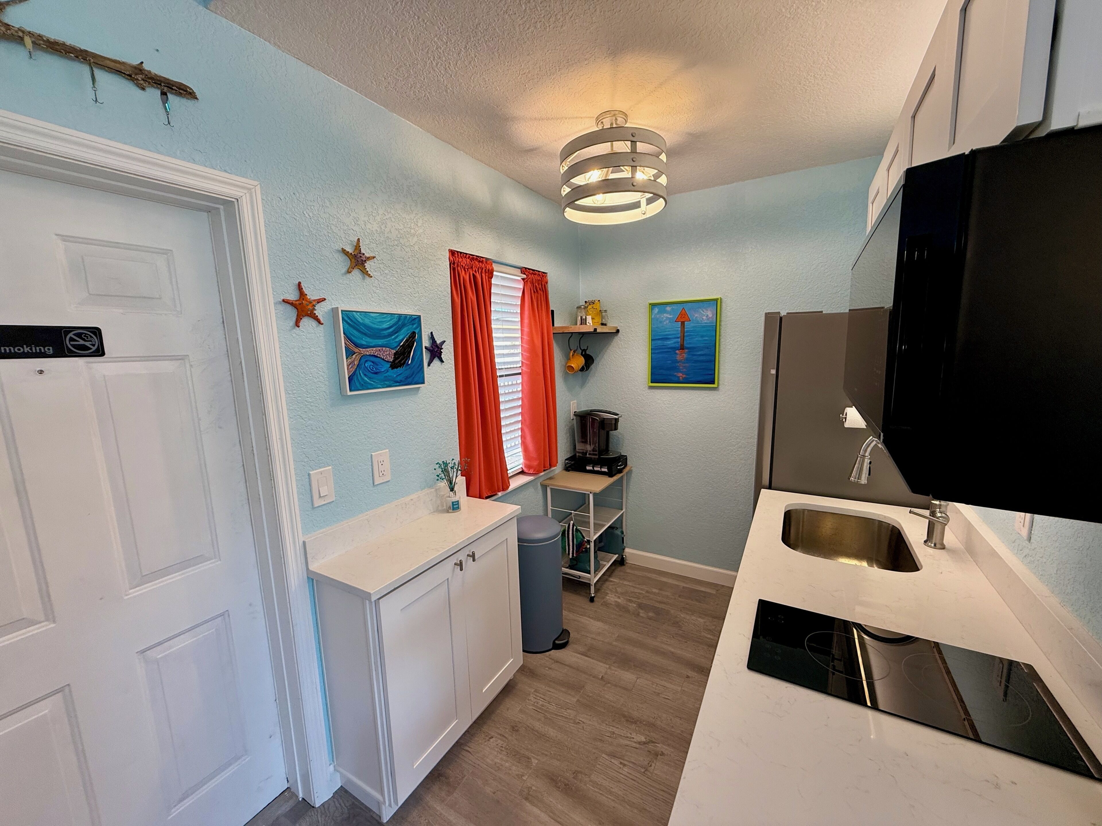 A compact kitchen with a sink, a coffee maker, and a television.