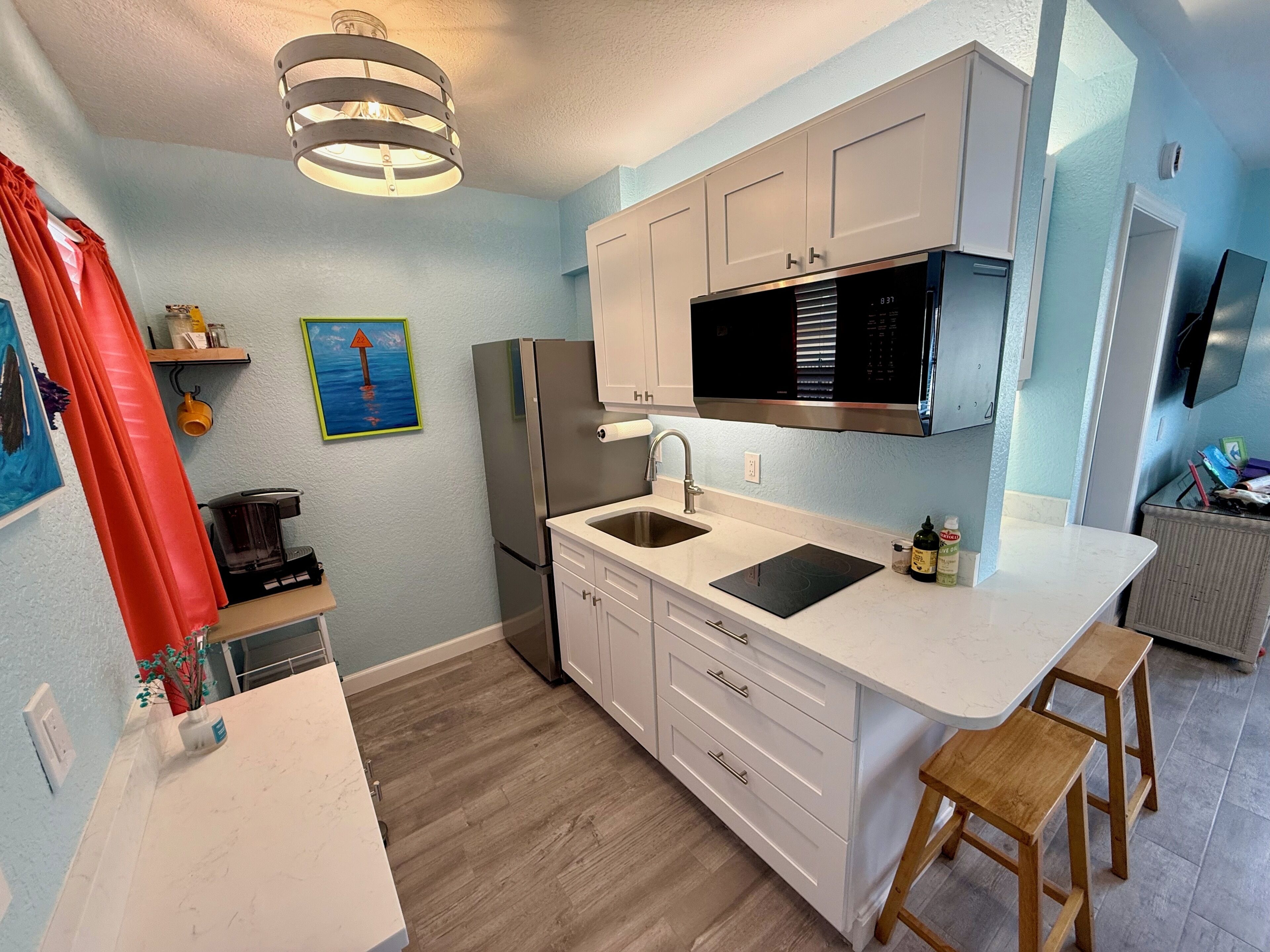 A modern kitchen with a stainless steel refrigerator, double sink, and a microwave above the counter.