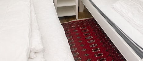 A room with two beds, a bedside table, and a wall-mounted lamp.