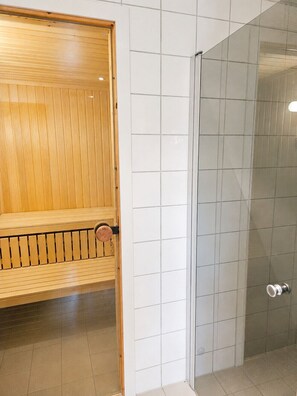 Eine Sauna mit einer Holzbank und einem gläsernen Duschbereich.