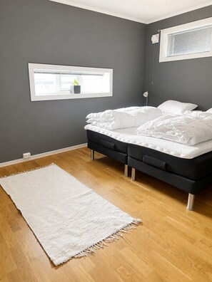 Ein Schlafzimmer mit einem Bett, einem Fenster, einer Nachttischlampe und einem weißen Teppich.