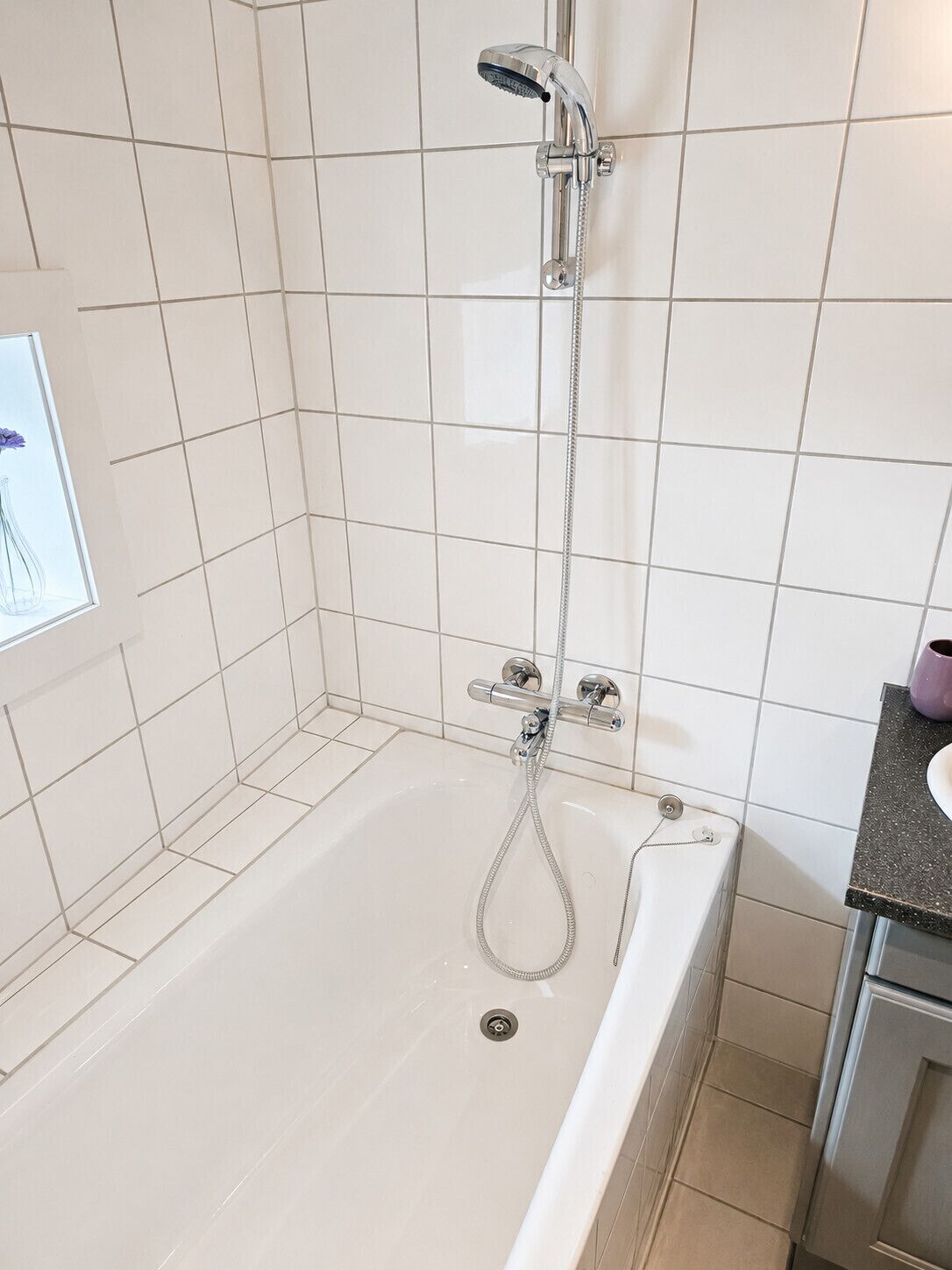 A bathroom with a bathtub, a shower head, and a sink.