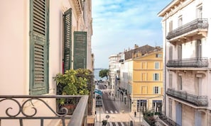 Eine schmale Straße mit Gebäuden an beiden Seiten, Balkone mit Metallgeländern und einem klaren Himmel.