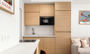 Eine moderne Küche mit Holzausstattung, einer schwarzen Mikrowelle und einer weißen Arbeitsplatte.