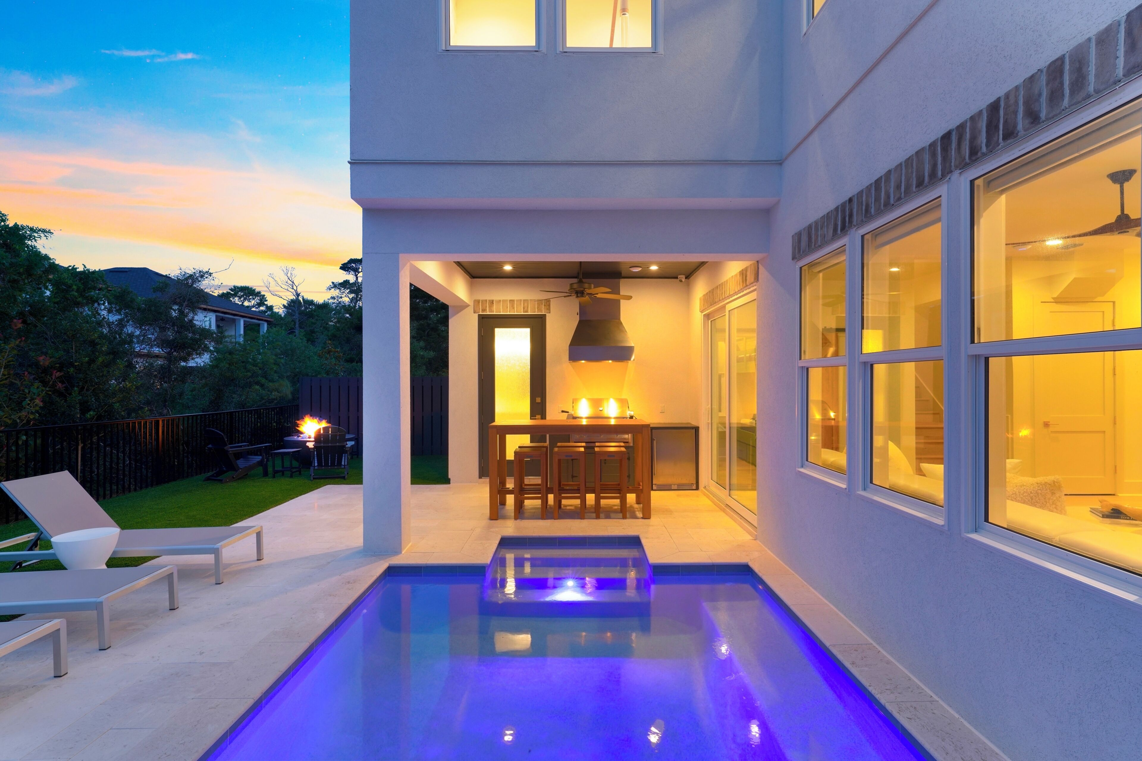 A modern house with a pool, outdoor seating, and a dining area.