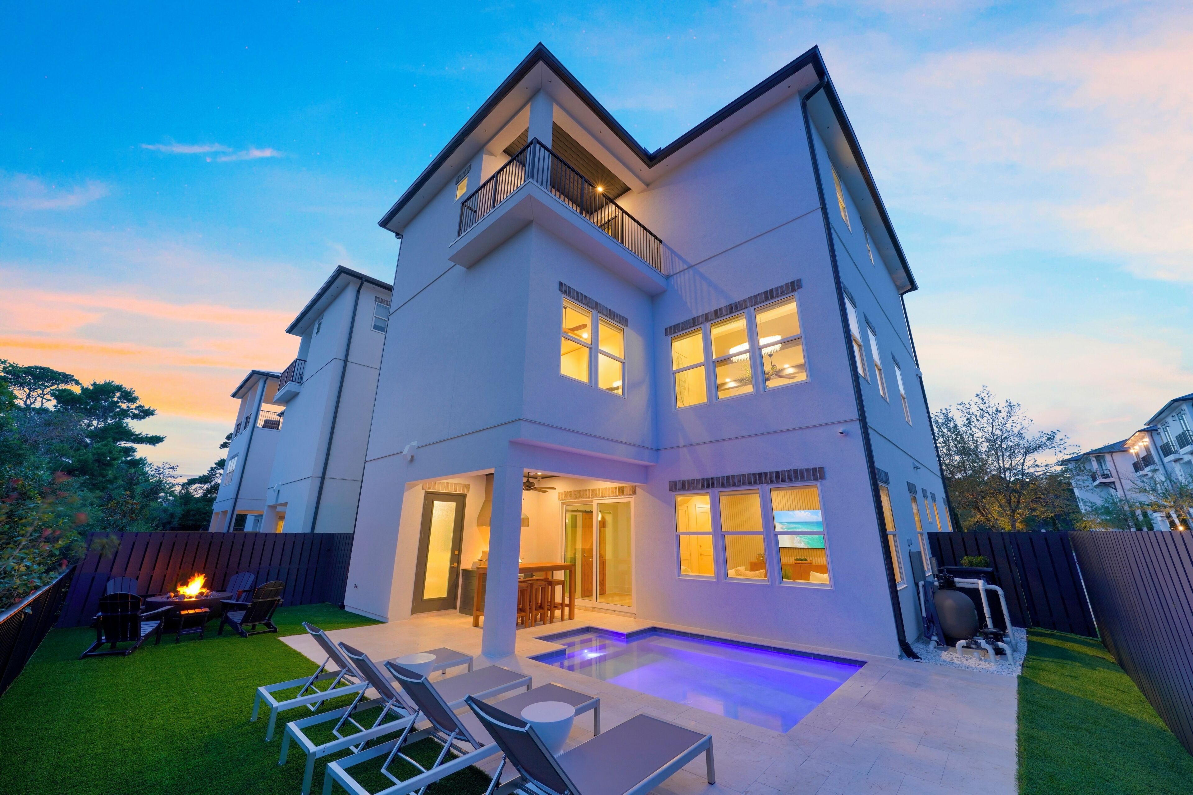 A modern two-story house with a covered patio, outdoor seating, and a swimming pool.
