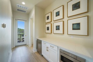 A kitchen with white cabinets, a stainless steel refrigerator, and a built-in oven. There are six framed pictures on the wall. - New Luxury 30A Beach Home plus Pool and more. (Santa Rosa Beach)