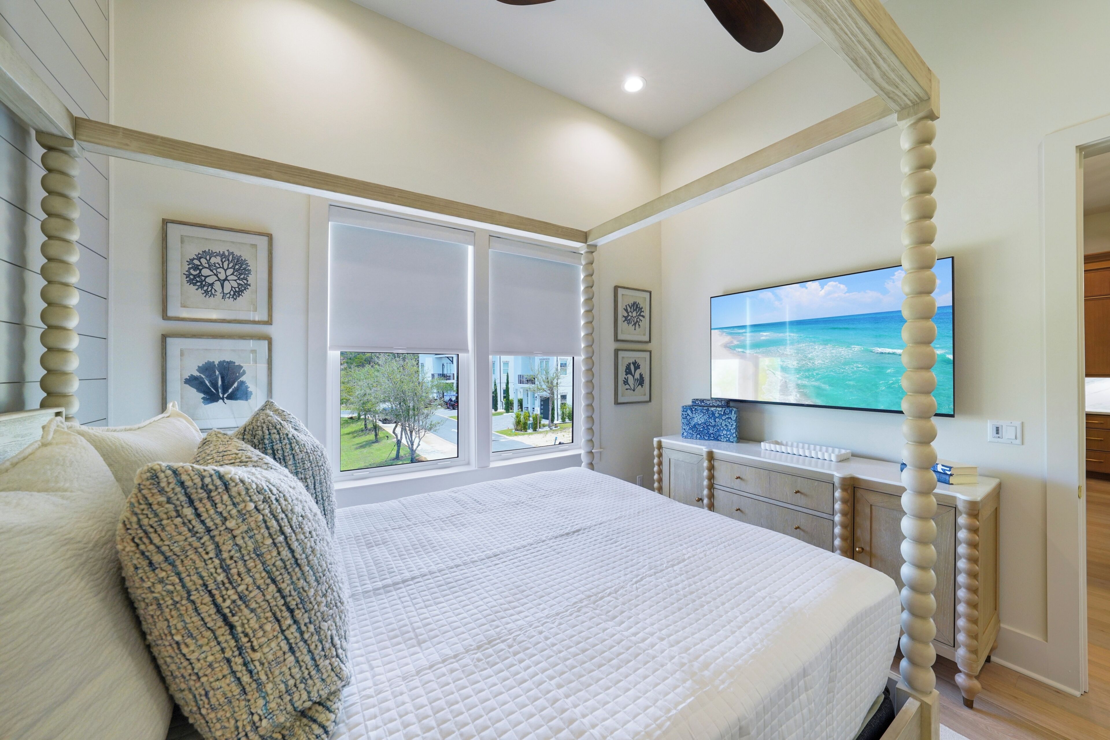 Un dormitorio con una cama grande, un televisor montado en la pared y vistas al exterior por la ventana.