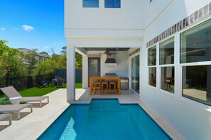 A modern house with a swimming pool, outdoor seating, and a barbecue area.