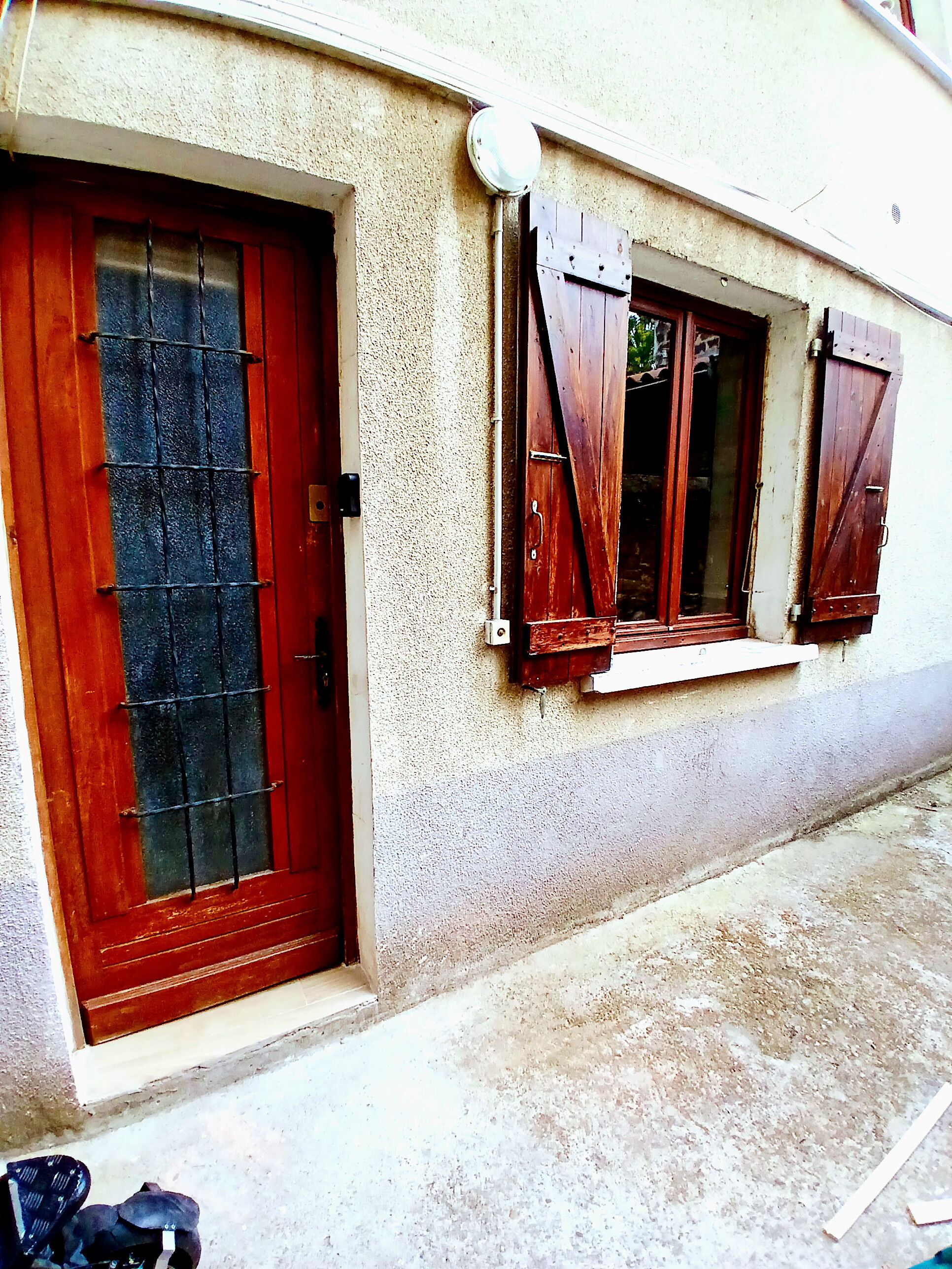 Un edificio con puerta roja y contraventanas de madera.