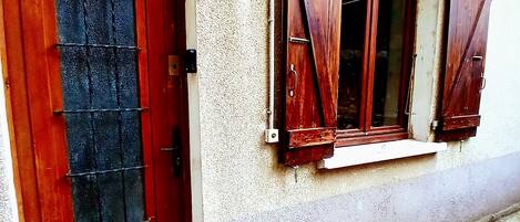 Un edificio con puerta roja y contraventanas de madera.