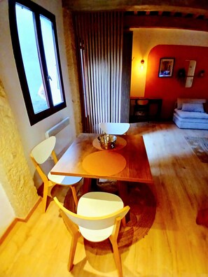 Ein Essbereich mit Holztisch und -stühlen, einem Fenster und einer roten Wand mit einem Bild.