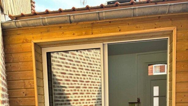 Un espace patio avec une porte-fenêtre coulissante, une petite table à manger et un matelas gonflable rond.