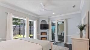 A bedroom with a bed, a ceiling fan, a TV, and a sliding glass door leading to a patio. - NEW! Beautiful home w/ private pool and golf cart! (Destin)
