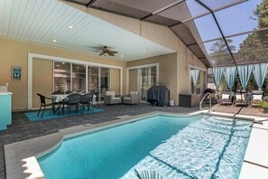 Ein Swimmingpool mit überdachter Terrasse, Sitzgelegenheiten im Freien und Deckenventilator.