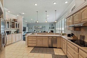 Een ruime keuken met een groot eiland, houten kastjes en een modern design.