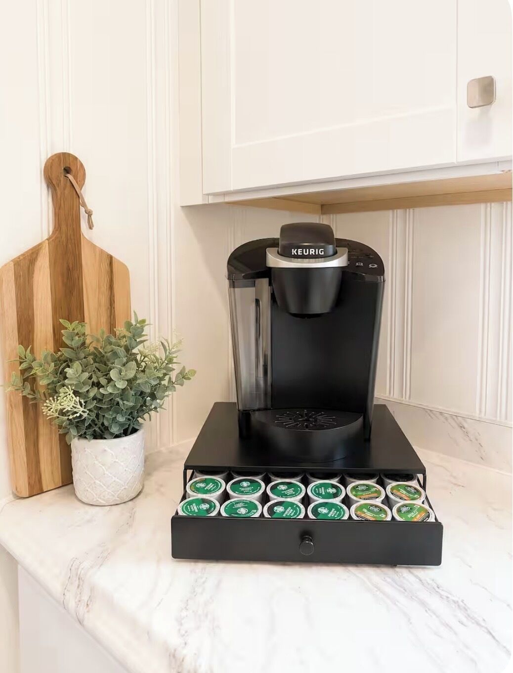 A coffee maker with a black base and a coffee pod holder below it.