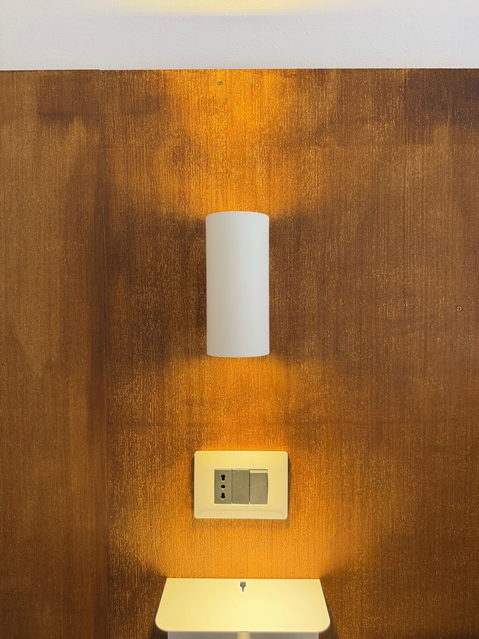 A wall-mounted light fixture and a control panel on a wooden wall.
