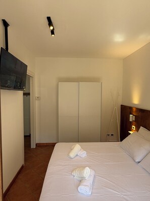 Ein Hotelzimmer mit einem Bett, zwei Handtüchern, einem Kleiderschrank und einem Fernseher.