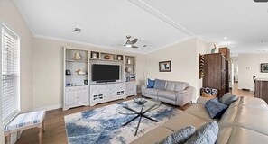 A living room with a television, sofa, coffee table, and a decorative cabinet. - Terrific 3-bedroom house in Port St. Joe with boat and camper parking (Port St. Joe)