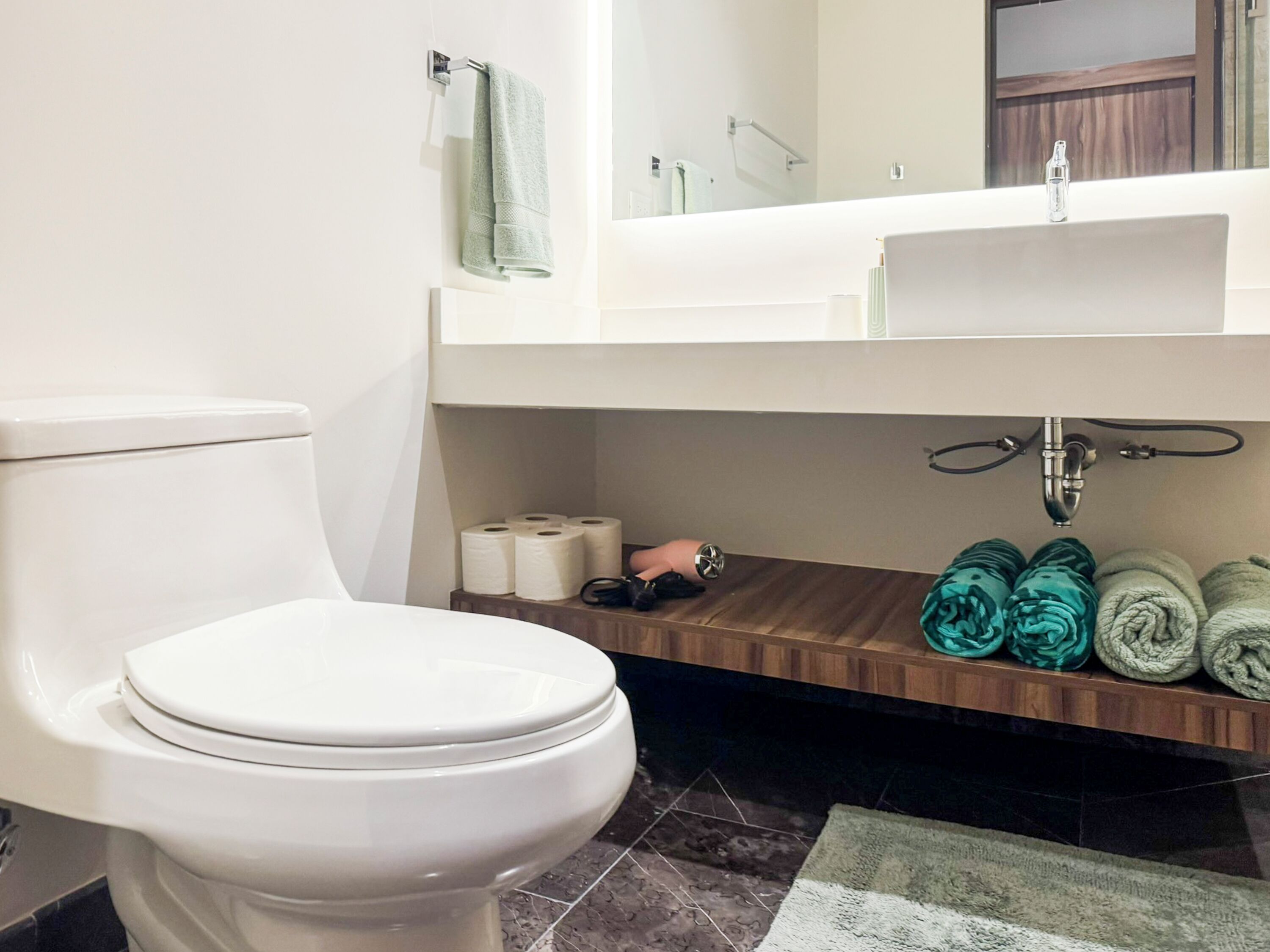 A bathroom with a toilet, a sink, and a mirror.