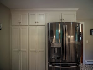 A stainless steel refrigerator with a water dispenser, white cabinetry, and a patterned floor. - Connecticut Beach Home (Old Lyme)