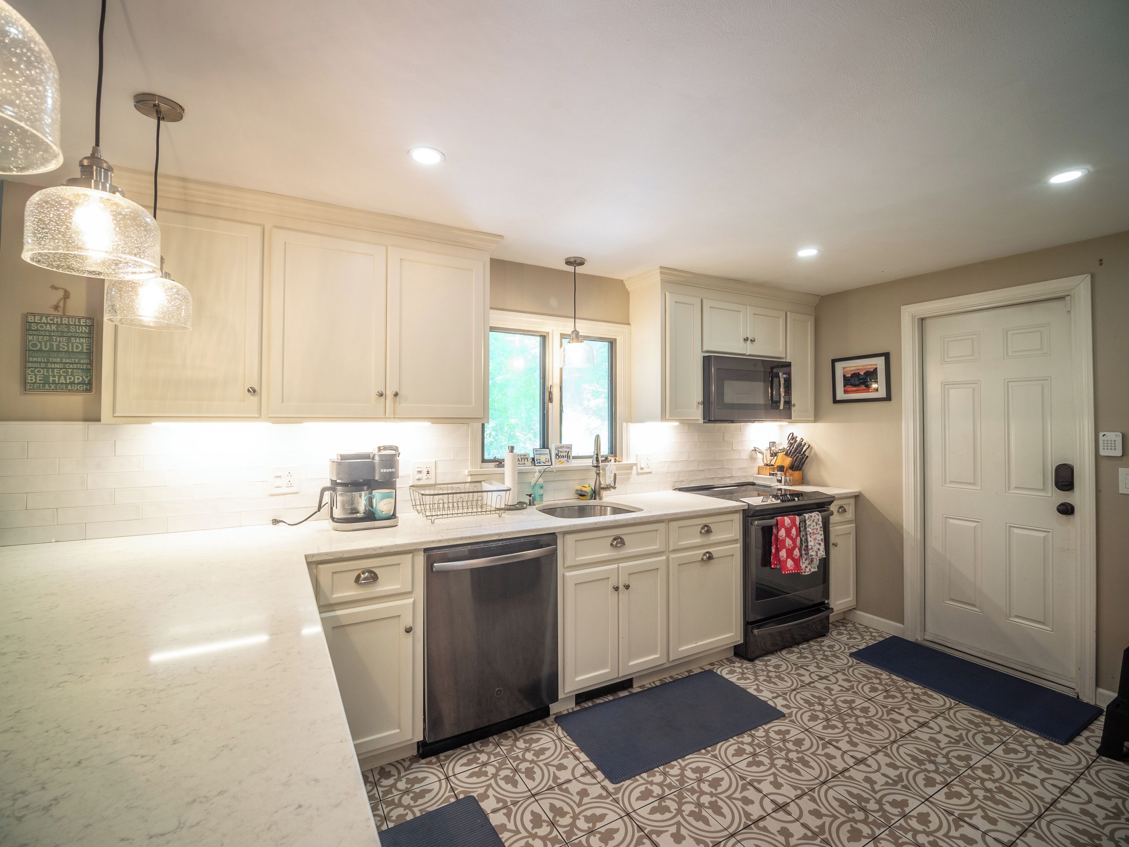A kitchen with white cabinets, a stainless steel dishwasher, a microwave, and a coffee maker.