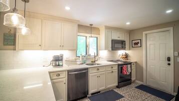 A kitchen with white cabinets, a stainless steel dishwasher, a microwave, and a coffee maker.