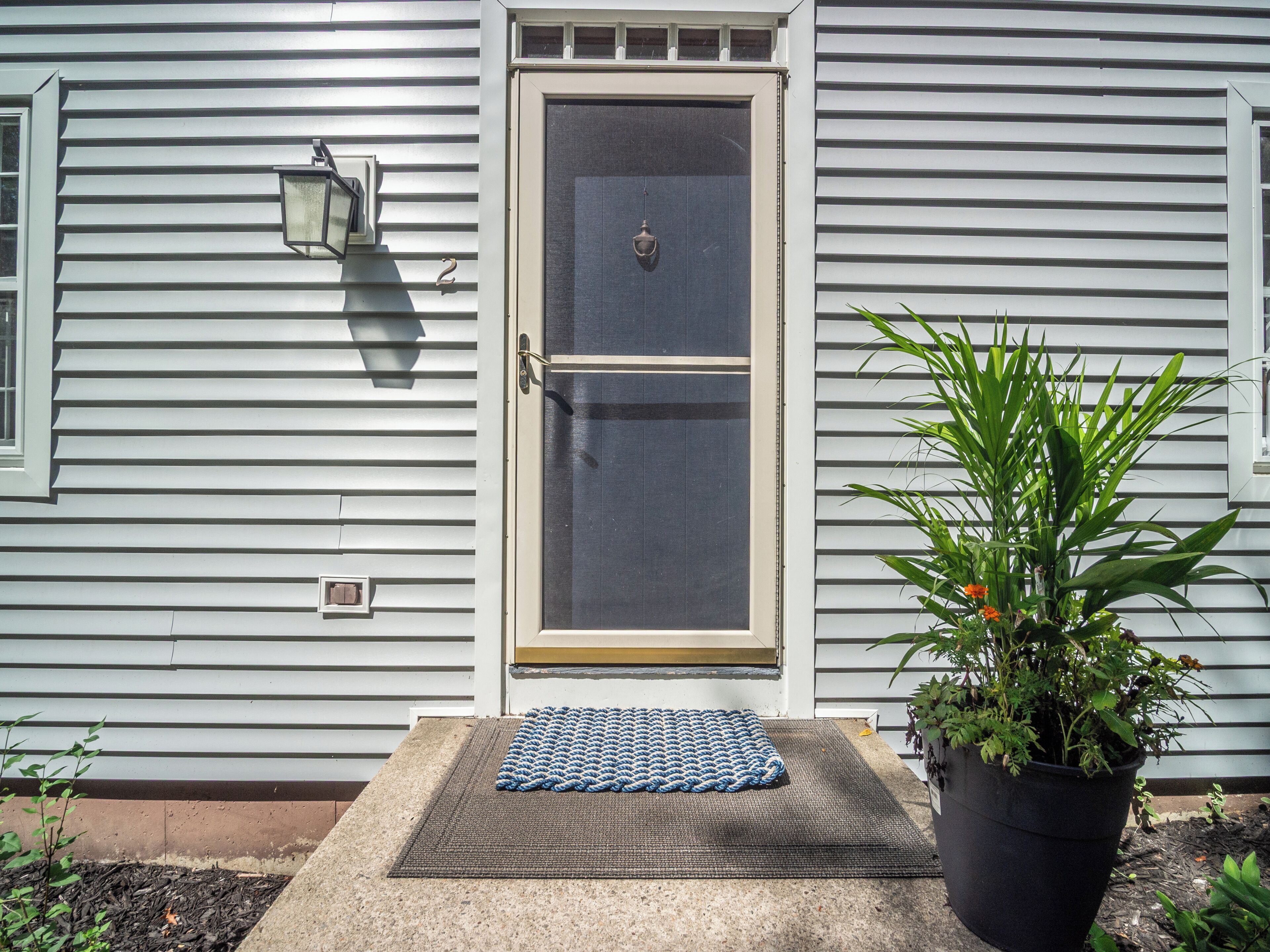 A house with a front door, a mailbox, a potted plant, and a doormat.