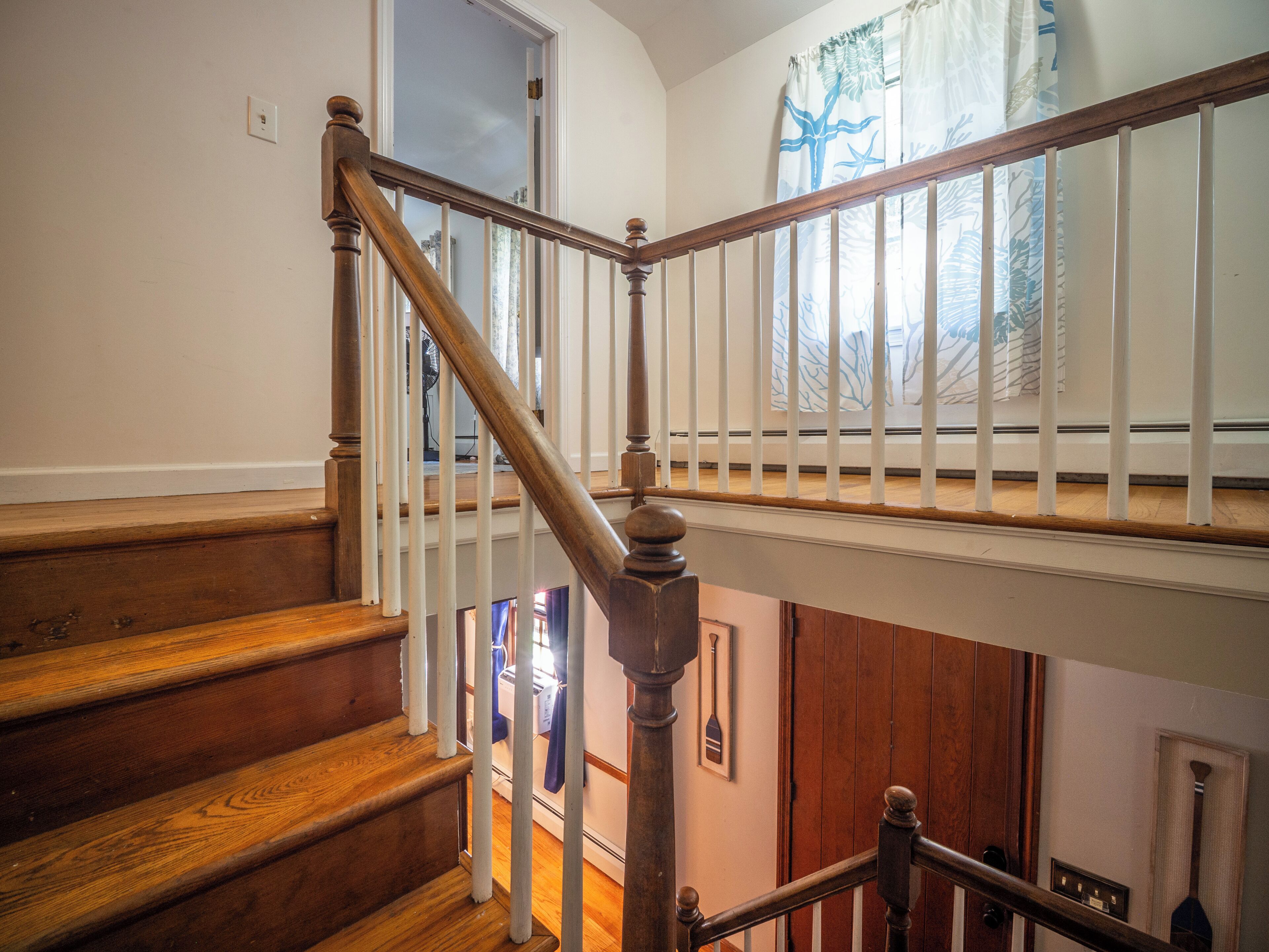 A wooden staircase with white railings and a view of the lower level.