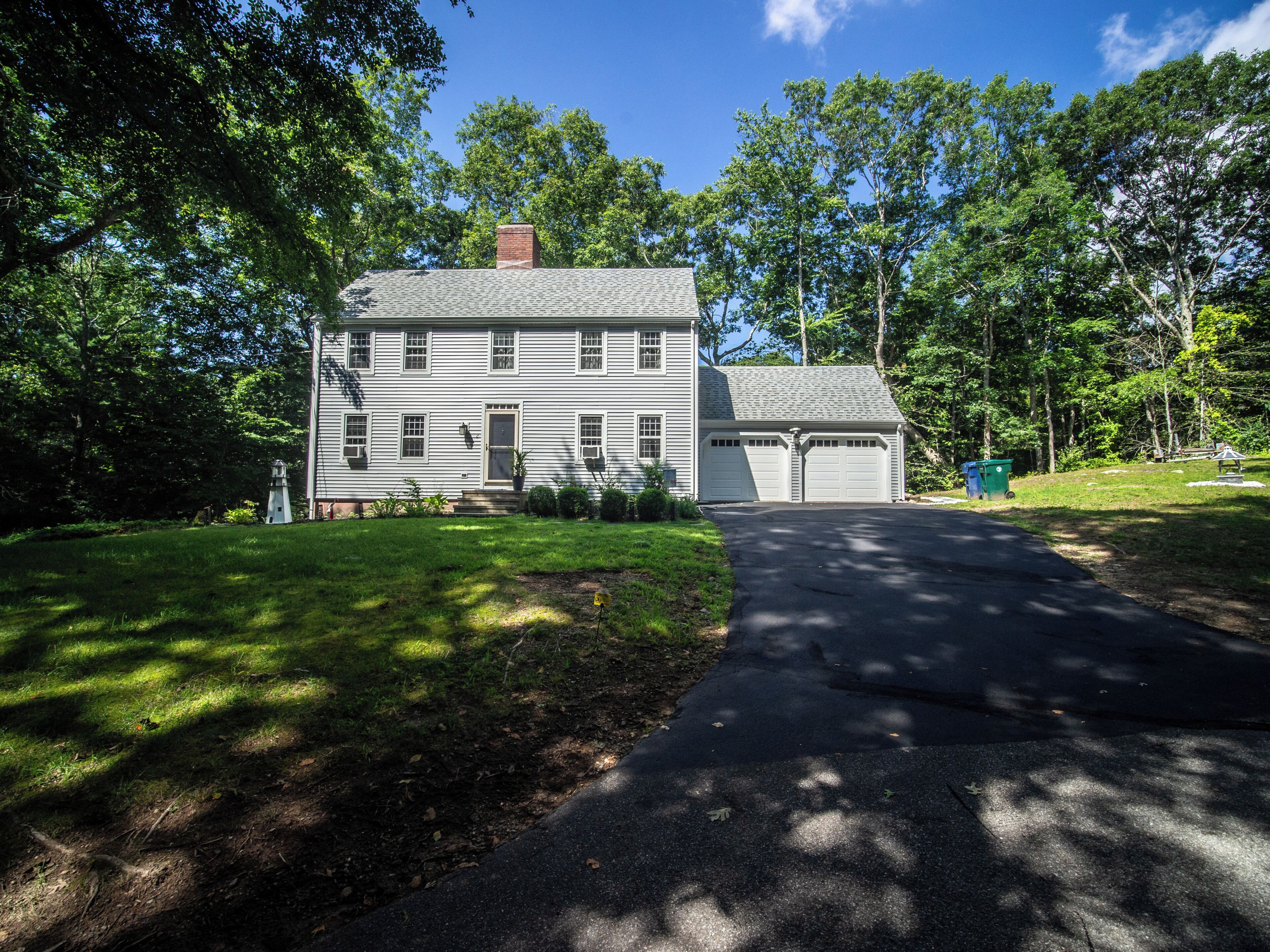 A two-story house with a garage, surrounded by trees and a well-maintained lawn.