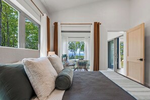 A hotel room with a large bed, a view of the outdoors, and a balcony with a table and chairs. - !New!-Sunset Escape- Bayside Bluff with Hot Tub (Egg Harbor)
