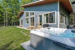 A house with a hot tub in the backyard, a deck, and a wooden staircase leading to the entrance. - !New!-Sunset Escape- Bayside Bluff with Hot Tub (Egg Harbor)