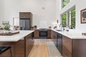 A modern kitchen with a central island, built-in appliances, and a view of the outdoors. - !New!-Sunset Escape- Bayside Bluff with Hot Tub (Egg Harbor)