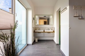 Ein modernes Badezimmer mit einem großen Spiegel, zwei Waschbecken und einer kleinen Mülltonne.