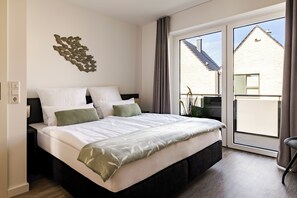 Ein Schlafzimmer mit Bett, Wandbild und Ausblick nach draußen.
