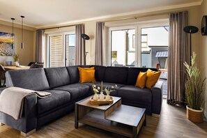 Ein modernes Wohnzimmer mit einem Ecksofa, einem Couchtisch und einem Essbereich mit Tisch und Stühlen.