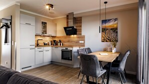 A modern kitchen with white cabinets, a wooden countertop, and a built-in oven. - A Getaway in Büsum - Vacation Home with Sauna & Fireplace (Büsum)
