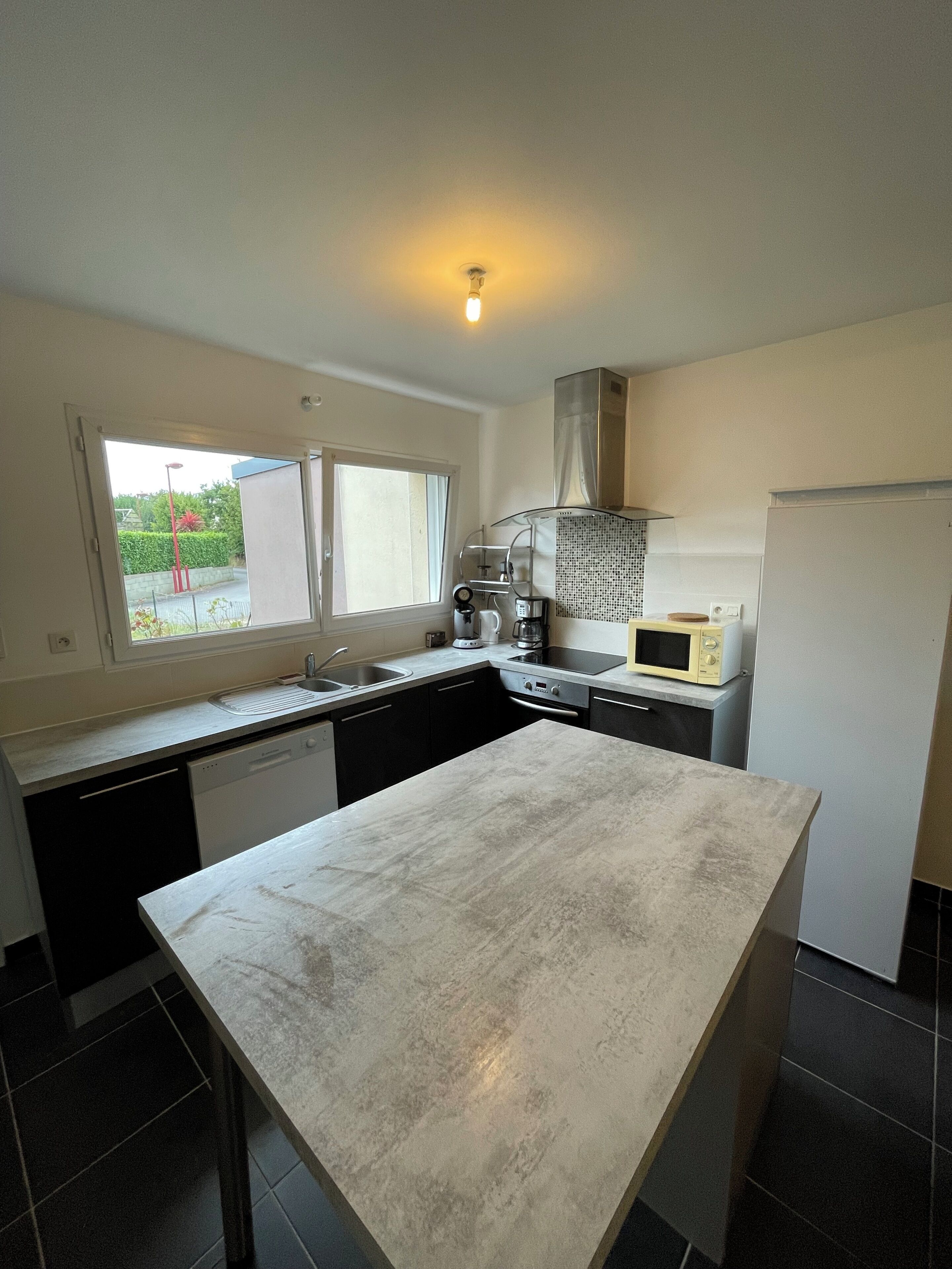 A modern kitchen with a central island, a microwave, and a stove.