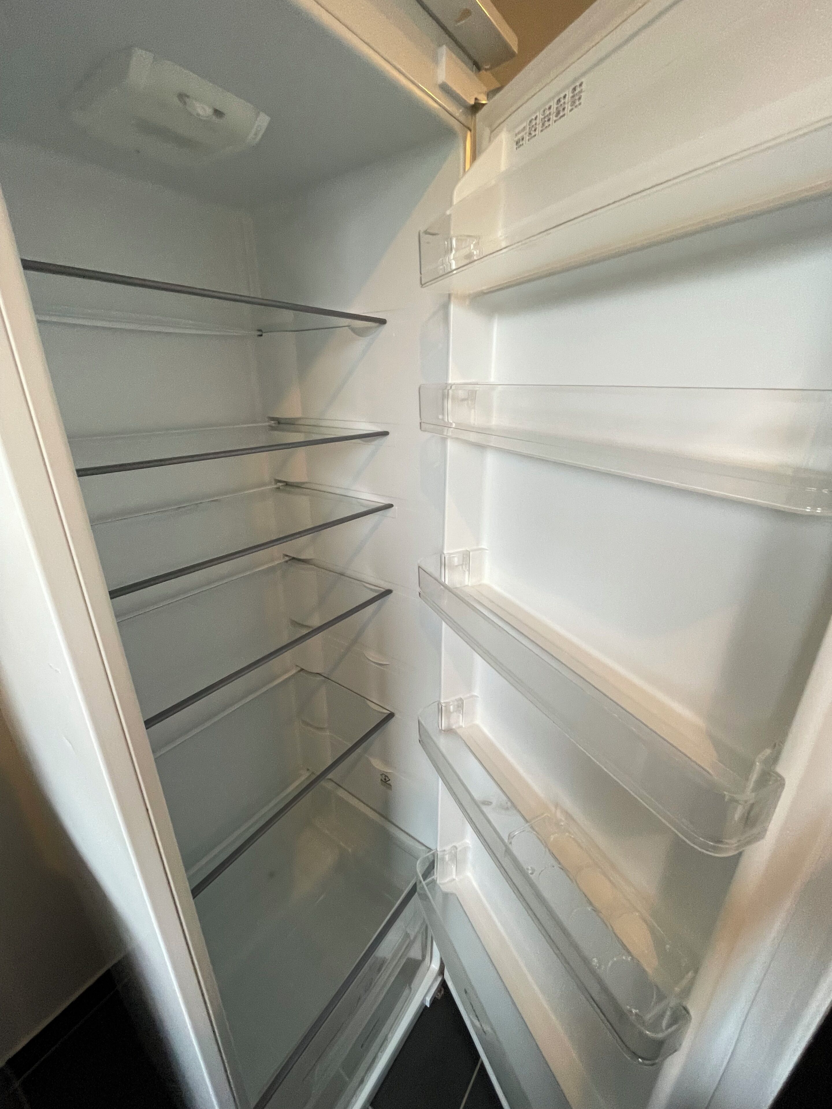 An empty refrigerator with multiple transparent shelves.