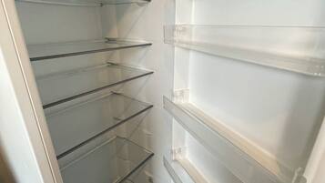 An empty refrigerator with multiple transparent shelves.