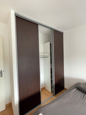 Un dormitorio con cama, armario con puertas correderas y espejo.