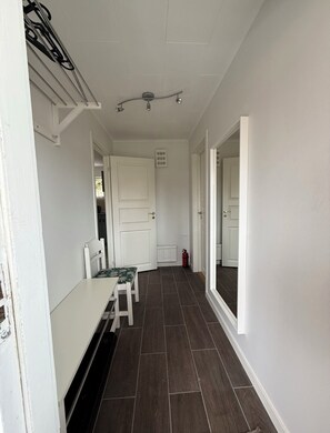 A hallway with a white door, a bench, and a radiator.