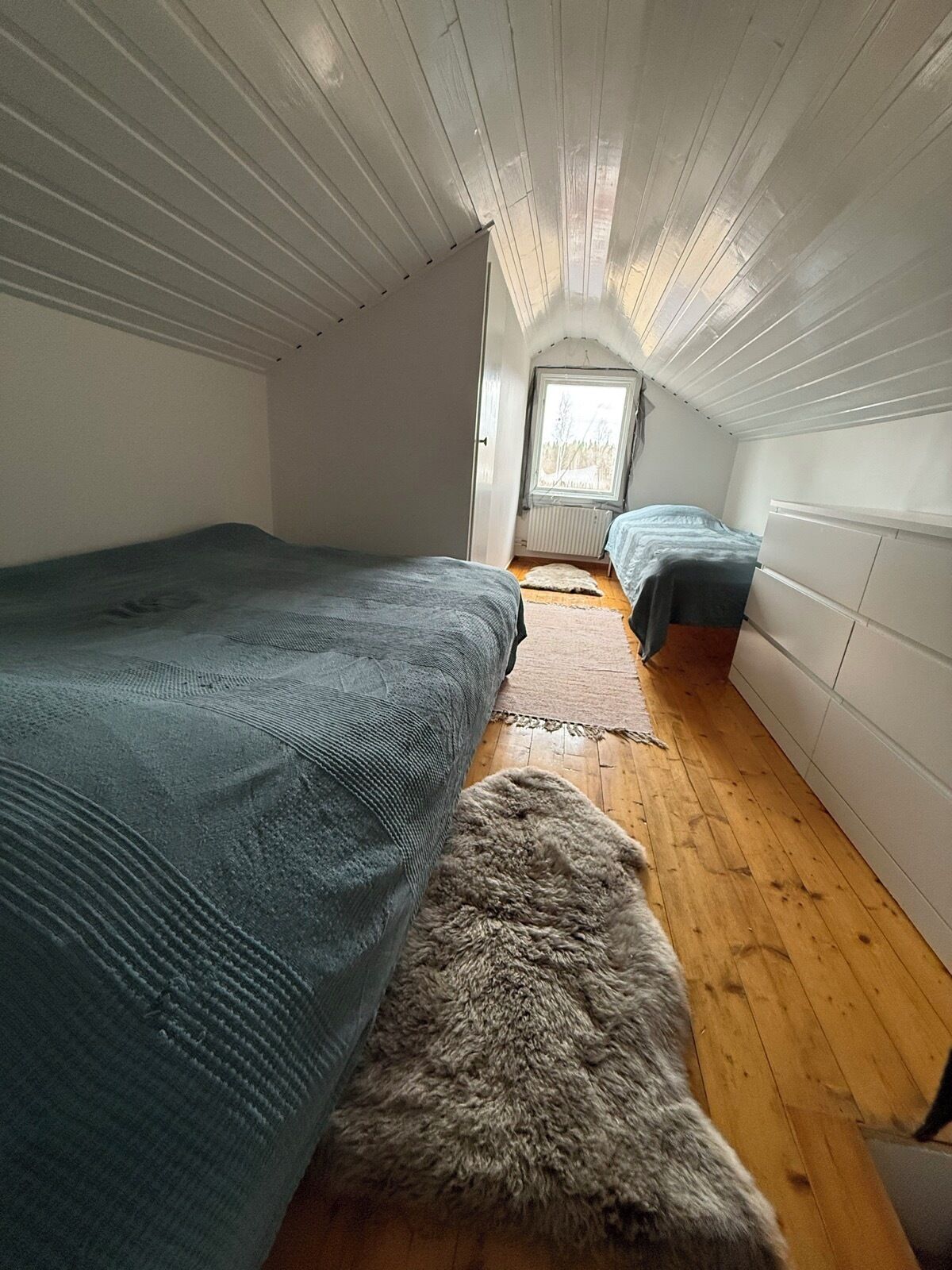 Un dormitorio abuhardillado con dos camas, suelo de madera y techo inclinado.