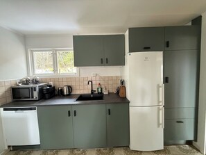 A compact kitchen with a microwave, kettle, and refrigerator.