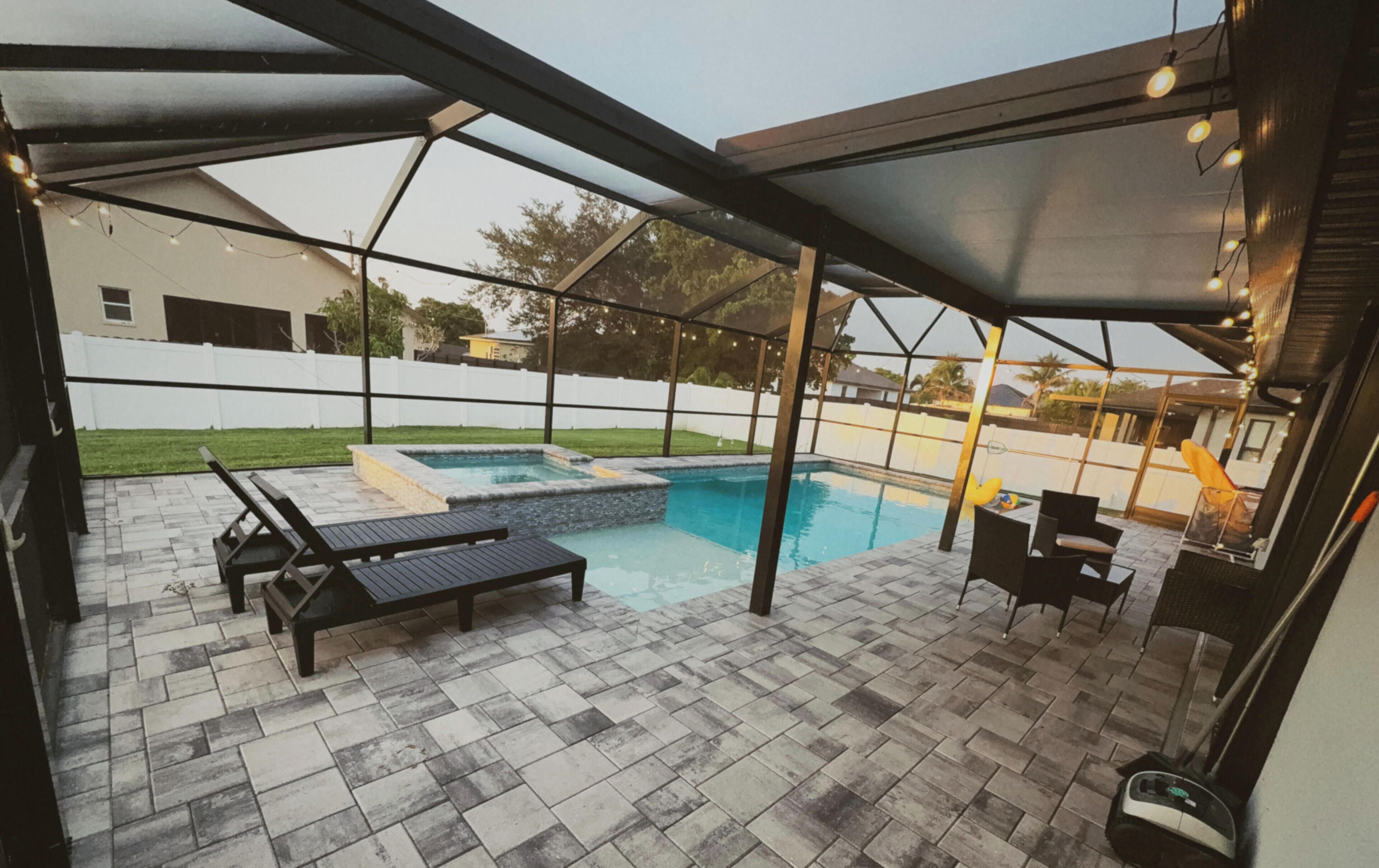 Zona de piscina exterior cubierta con sillones de descanso y un jacuzzi.