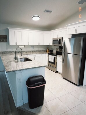A kitchen with white cabinets, a stainless steel refrigerator, a microwave, and a sink. - Bessa Sol Retreat - Heated Pool & Spa - Boat parking (Cape Coral)